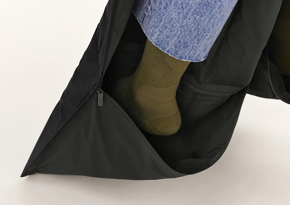 A foot shown inserted into the pocket of a travel blanket.