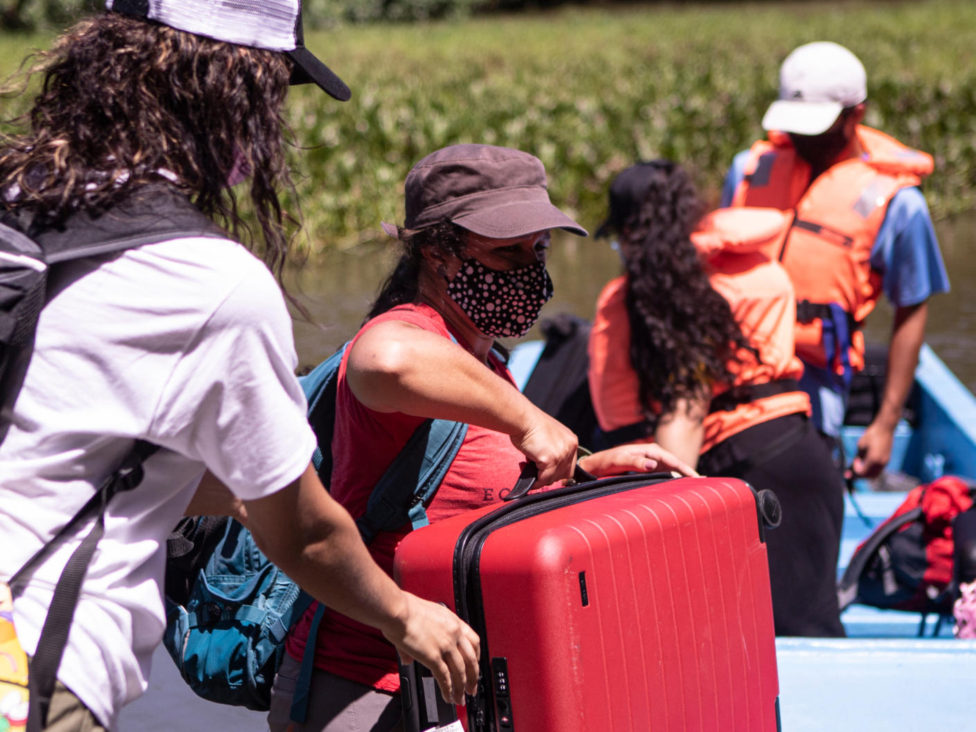 Away volunteers carrying the Away suitcase onto a boat