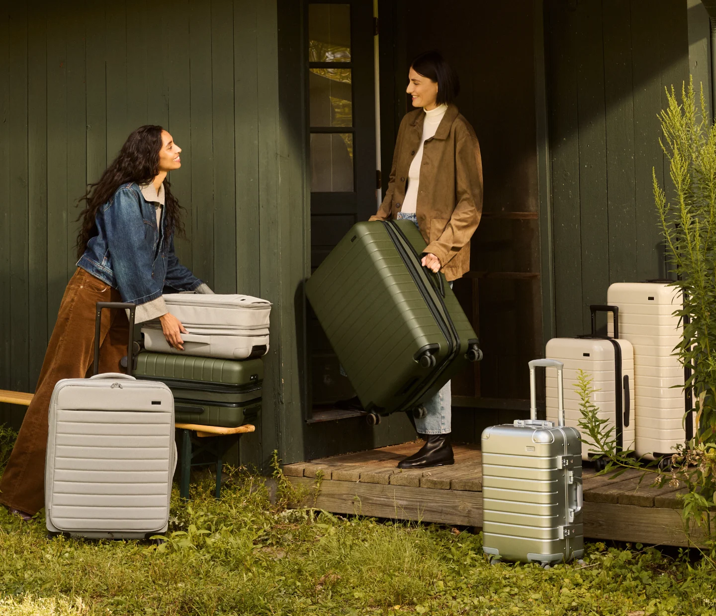 Two people carrying multiple Away luggage in front of a cabin