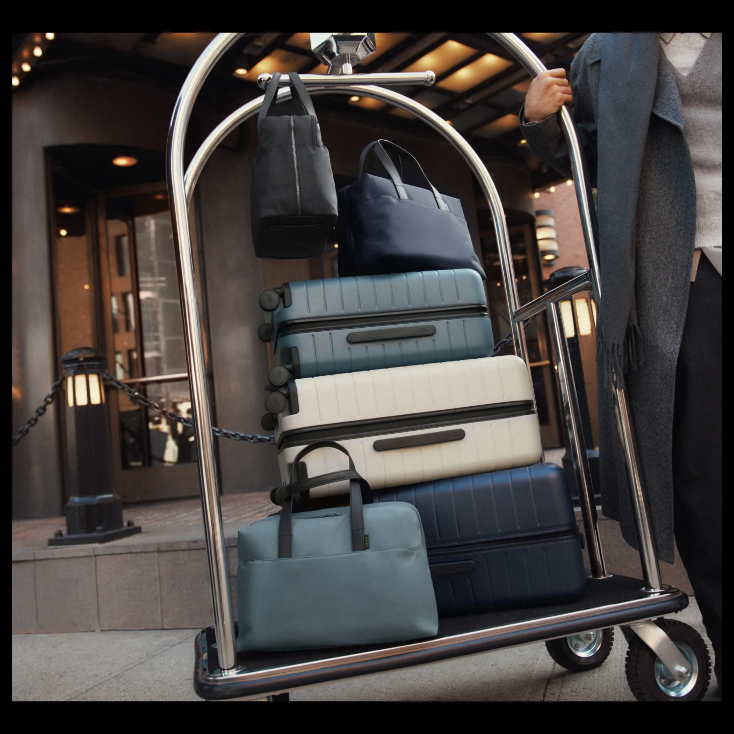 An assortment of Away luggage and travel duffle bags on a hotel luggage cart