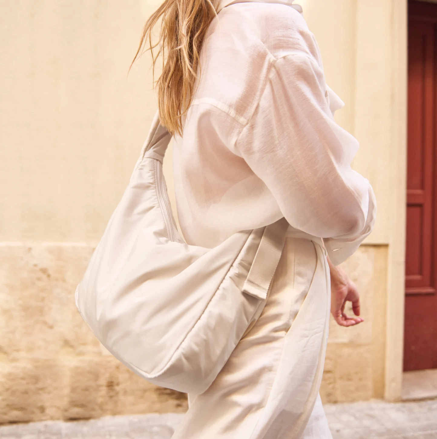 Person wearing Away's lightweight Featherlight Crossbody bag in salt white