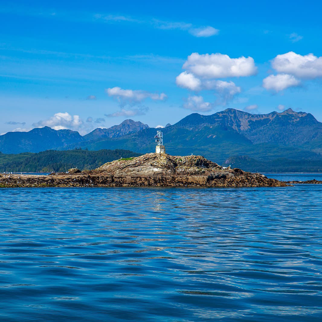 A view of the clear blue sea and The Haida Gwaii or Queen Charlotte Islands with white clouds in the sky.