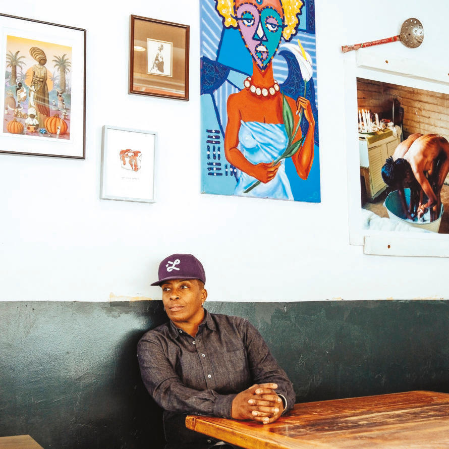 An Oakland chef sitting in a booth against a wall displaying modern art.