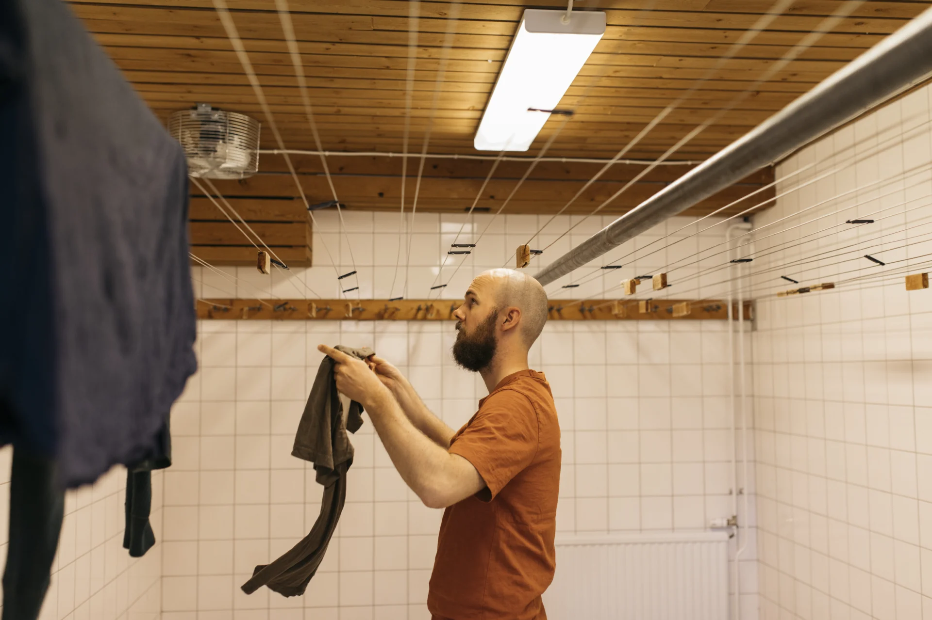 skäggig kille hänger tvätt i tvättstuga