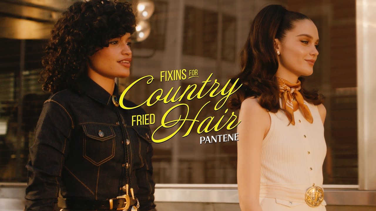 two women in 50s retro attire walking with the words “fixins for country fried hair” in yellow 
