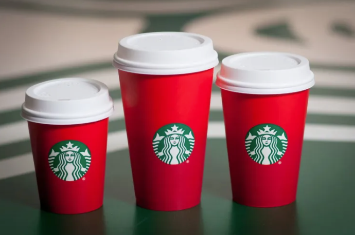 A set of three of Starbucks' controversial red holiday cup on a green table