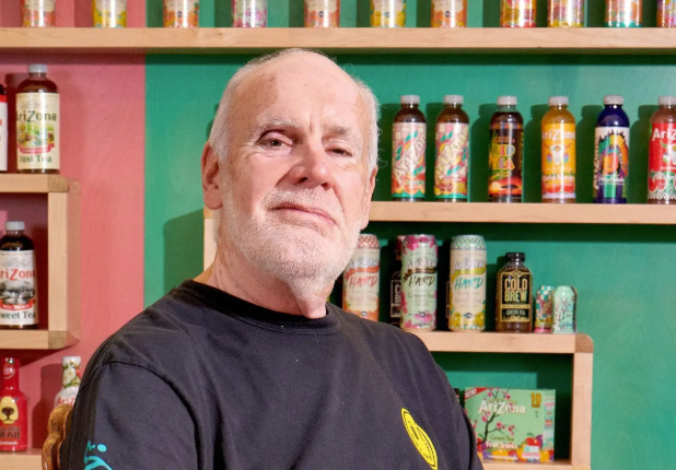 AriZona Iced Tea founder stands in front of wall of AriZona beverages
