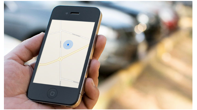 a white person’s hand holding a phone with the image of a map with a blue dot on it 