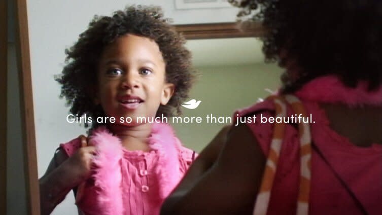 Still image from Dove's 2025 Change the Compliment ad showing a little girl with a pink shirt and pink feather boa