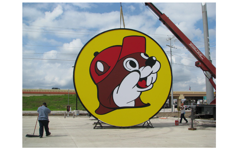 A photo of a sign with the Buc-cee’s logo, a cartoon beaver wearing a red cap on a yellow circle