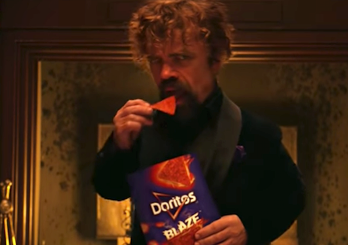 Peter Dinkaridge features in Super Bowl Commercial with a bag of Blaze Doritos, against a fireplace.