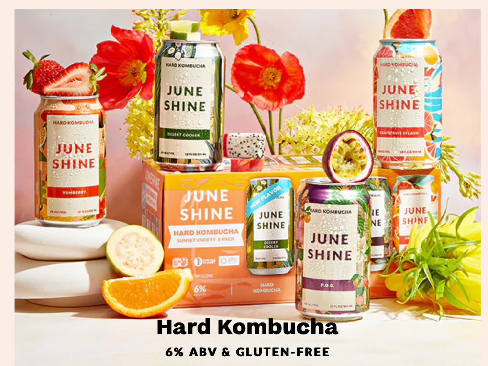 JuneShine selection of drinks positioned among flowers and fresh fruit. 