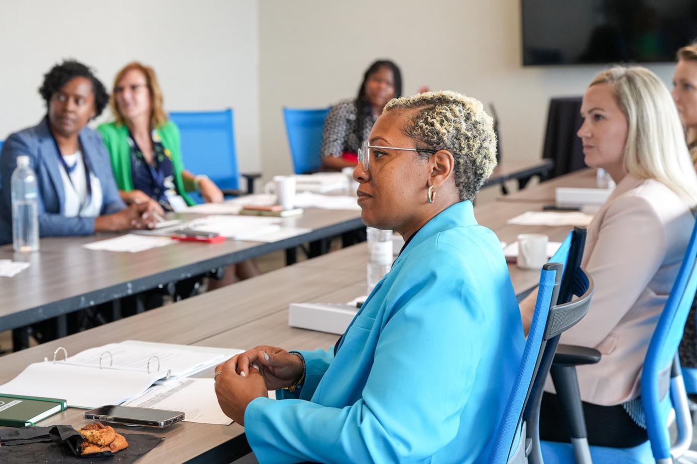 Women seated at a conference table, actively participating in a meeting, highlighting professional engagement and dialogue.