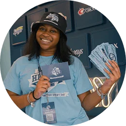 A young, black female college student holds up a blue card and P&G prize money. She is wearing a light blue t-shirt.