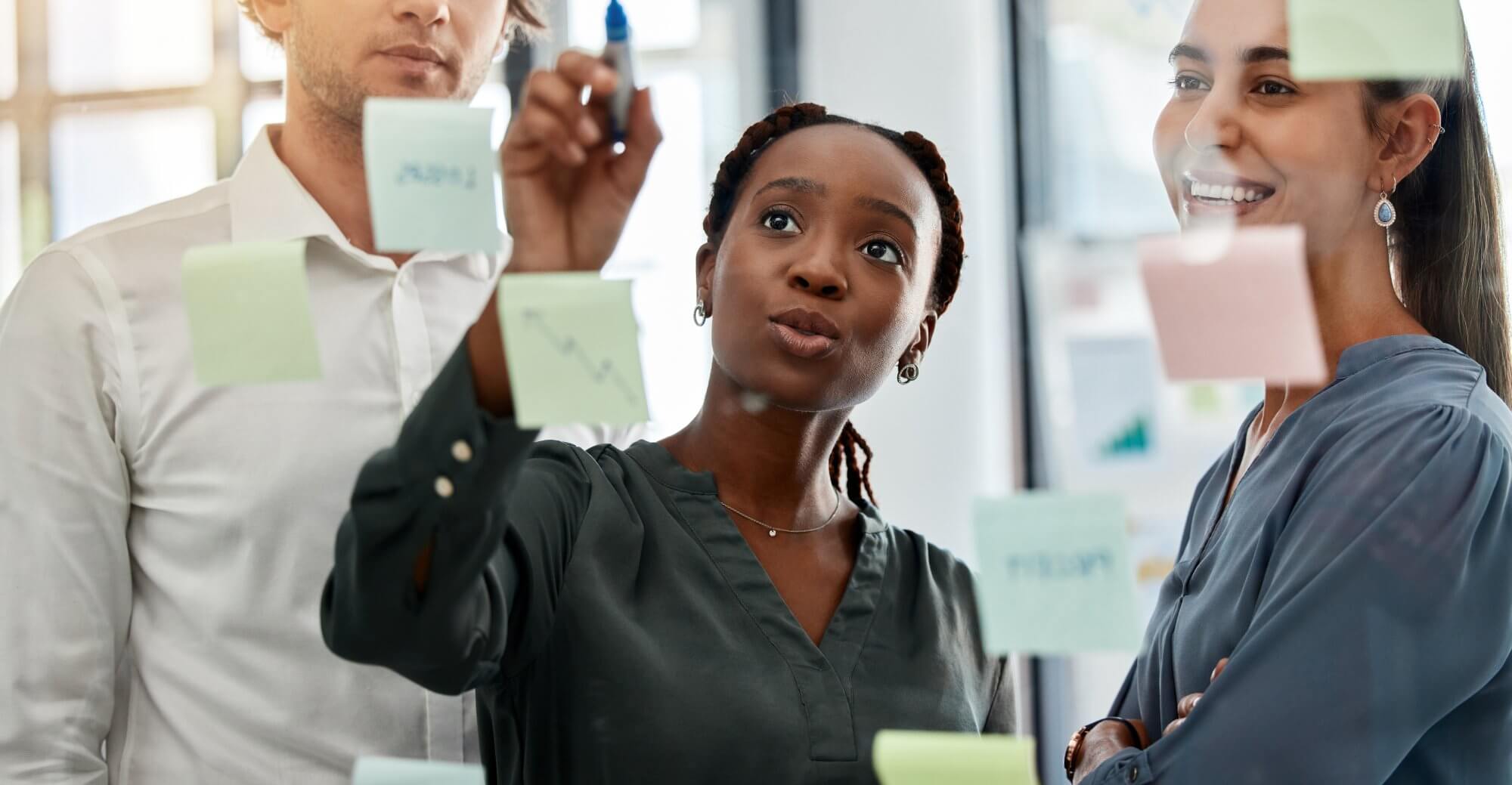 A diverse group of three individuals collaborating in an office and placing sticky notes on a glass wall. The main text overlay reads, "Respecting Human Rights at P&G." 