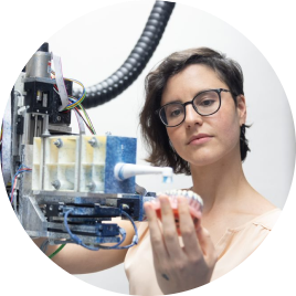 Woman with short wavy hair and glasses working with a device in a manufacturing