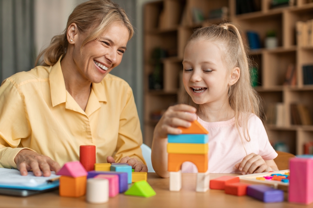 Therapist and young girl playing with building blocks 