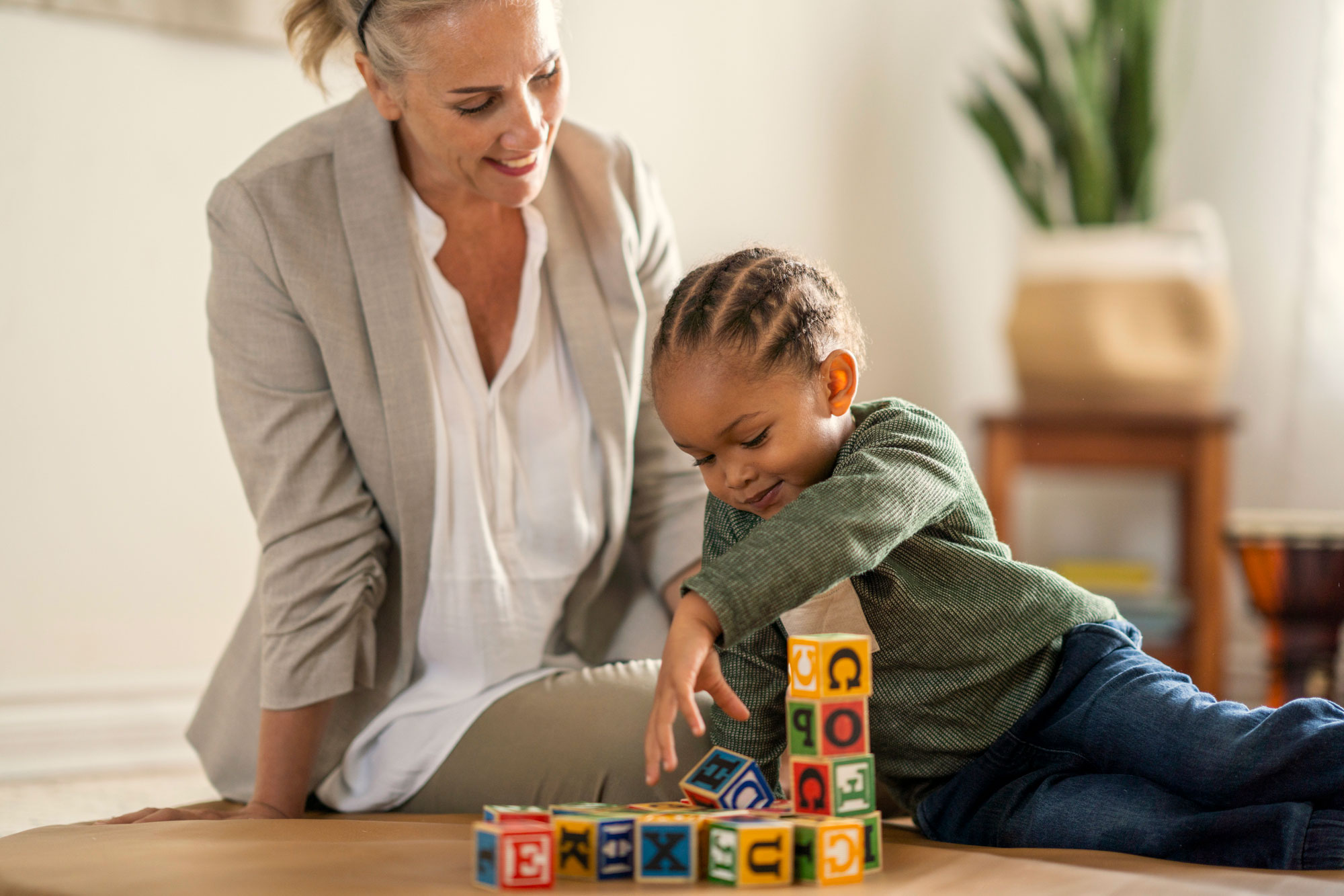 A woman observing a toddler playing with blocks