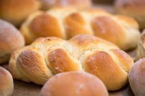 freshly baked challah surrounded by other rolls on a table