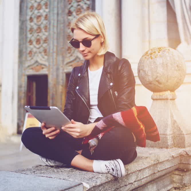 Studierende sitzt auf Mauer an der Uni und lernt