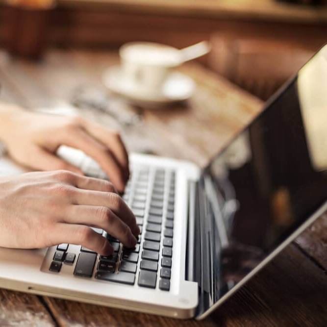 Studierende Person tippt etwas auf dem Laptop ab
