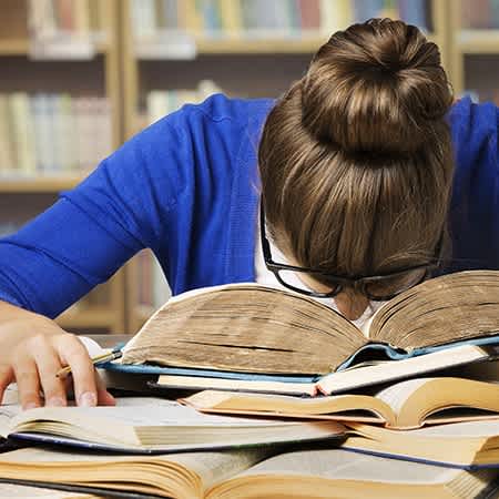 Studierende versinkt in Lernstress mit ihrem Kopf auf dem Tisch 