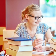 Studierende sitzt mit einem Becher Kaffee in der Bibliothek