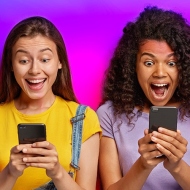 Zwei Studierende schauen begeistert auf ihre Handys