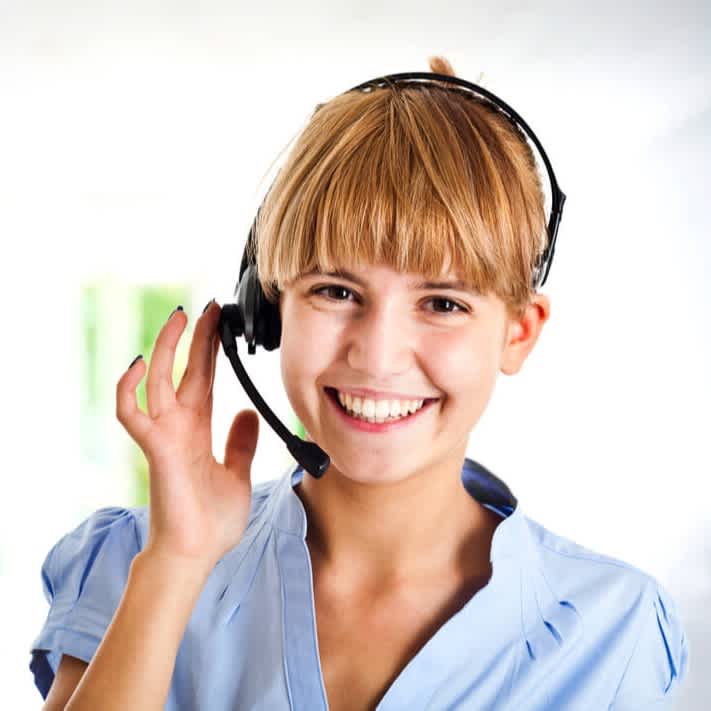 Callcenter Mitarbeitende mit Headset lächelt freundlich