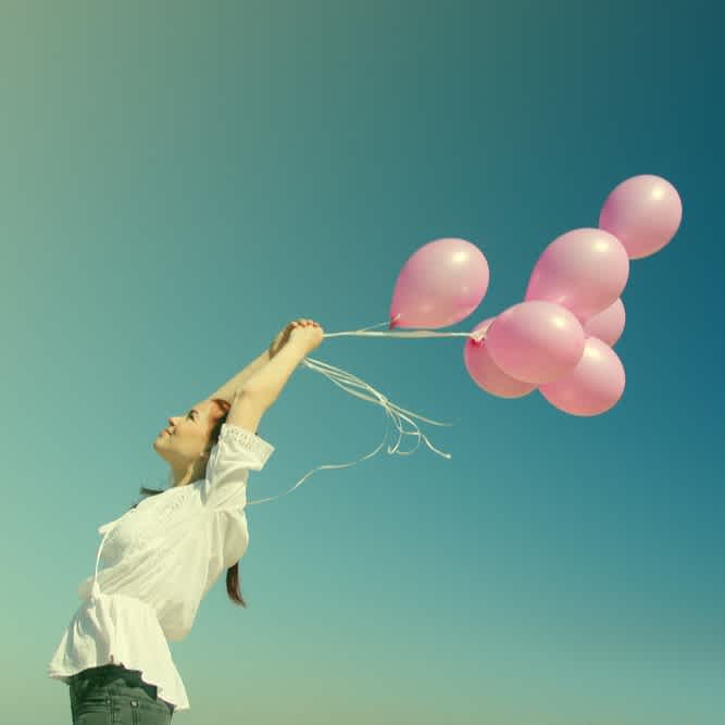 Studierende hält mehrere Luftballons in den Himmel