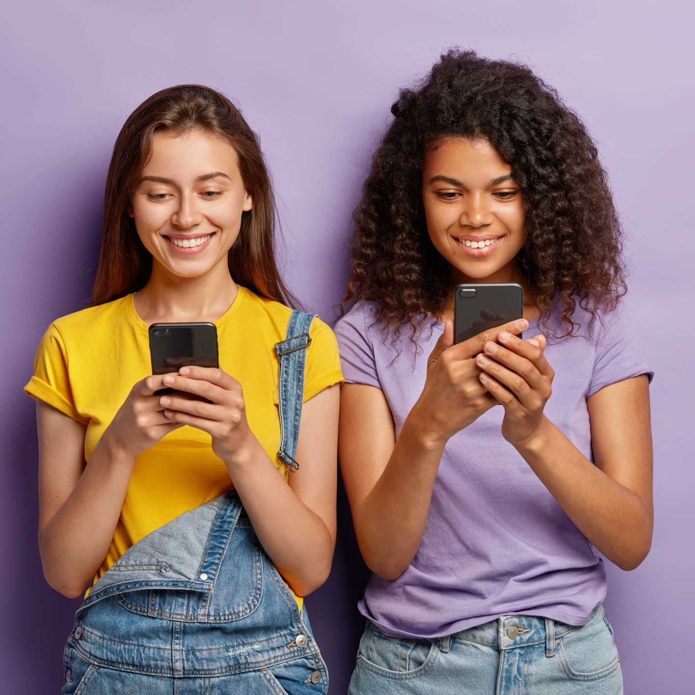 Zwei junge Frauen schauen lächelnd auf ihr Smartphone