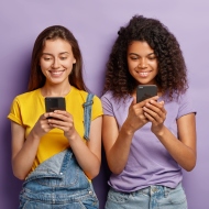 Zwei junge Frauen schauen lächelnd auf ihr Smartphone