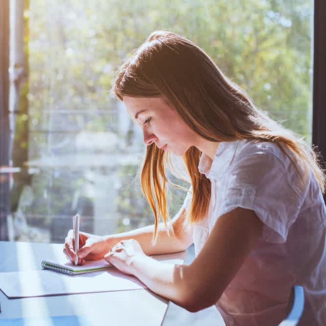 Studierende lernt am Fenster und fertigt Notizen an