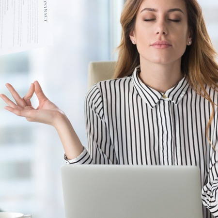 Mitarbeitende am Arbeitsplatz meditiert am Platz