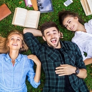 Studierende liegen beim Lernen zusammen auf der Wiese 