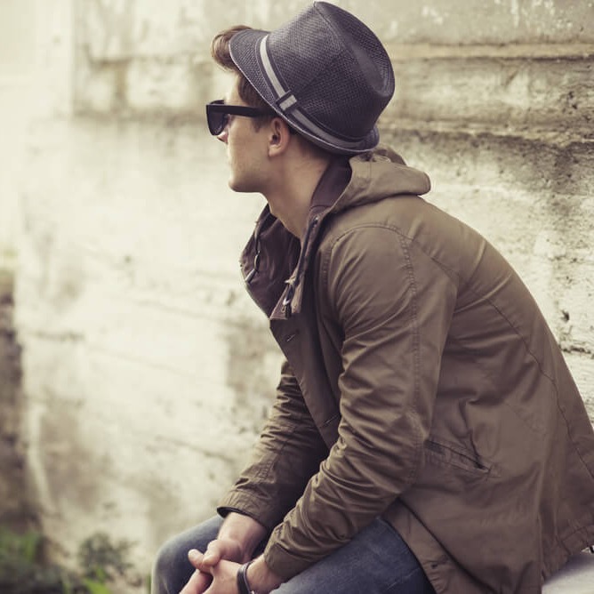 Studierender sitzt nachdenklich auf einer Mauer