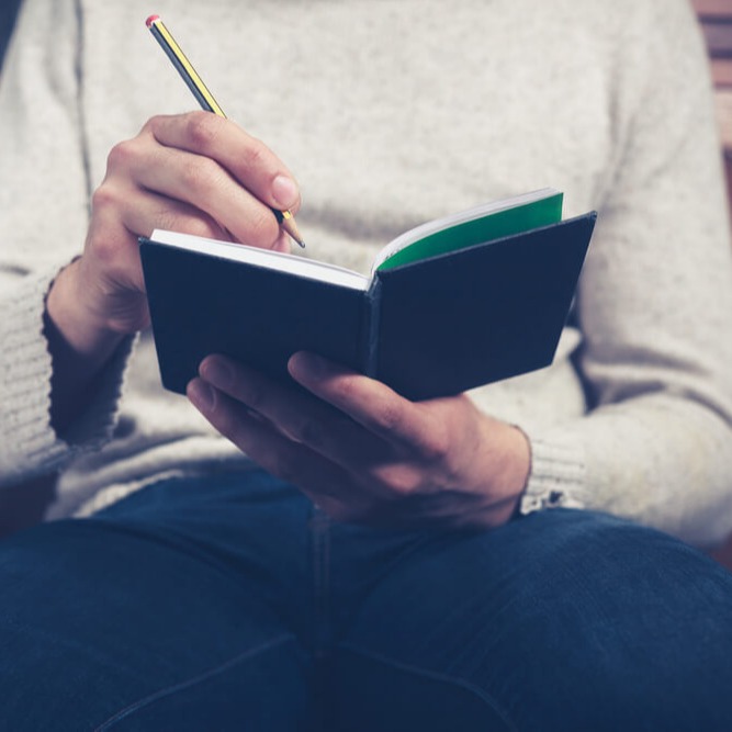 Dozierende*r sitzt gegenüber und schreibt ins Notizbuch