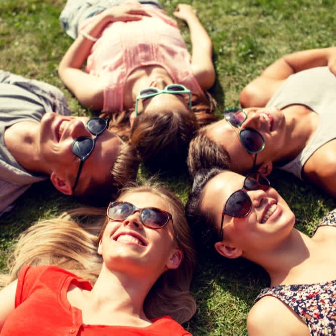 Befreundete Studierende liegen im Park in der Sonne