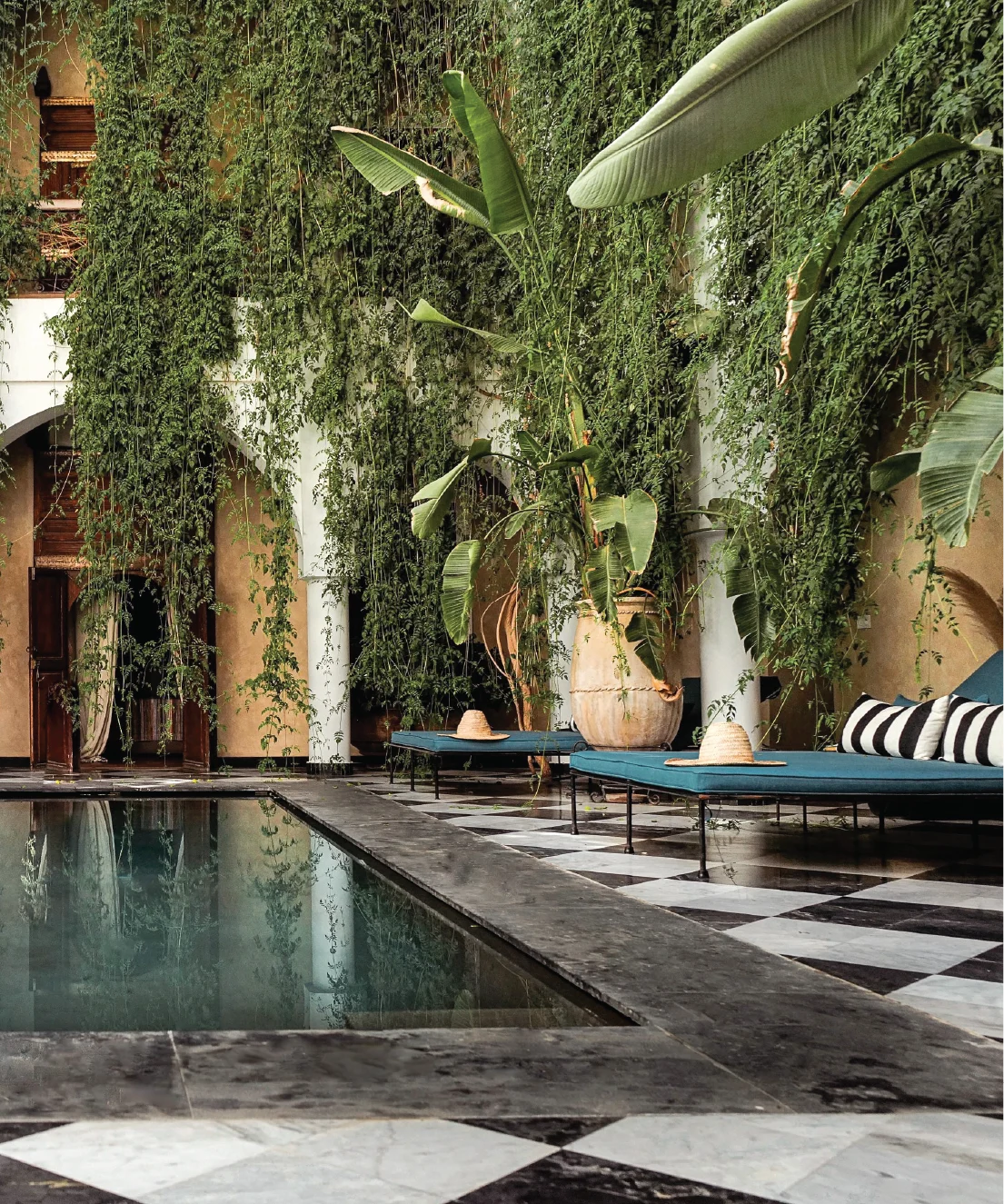 Full-page interior or architectural image with deep warm tones leaning toward terracotta and muted brown. Likely a moody riad or courtyard space with strong earthy character.