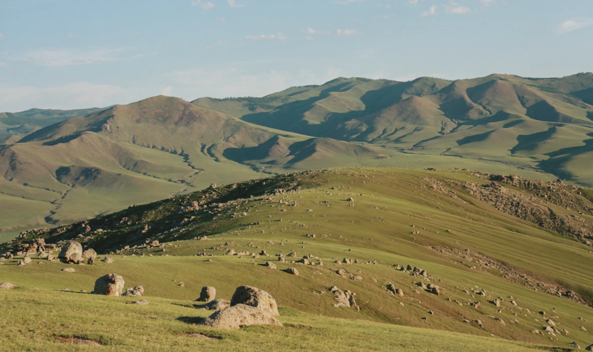 Expansive view of the Mongolian steppe under a vast blue sky, capturing the scale and openness of the landscape