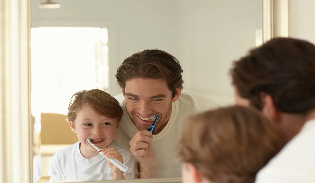 Father and kid brushing their teeth with Oral-B electric toothbrush article banner