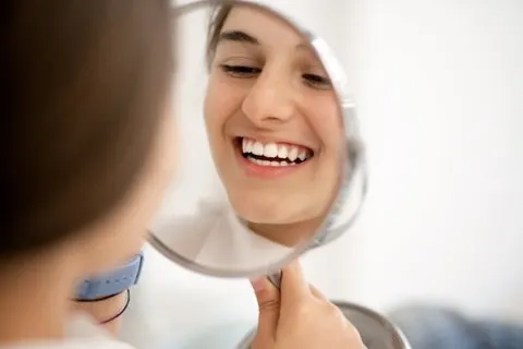 Woman looking at her teeth in a mirror article banner