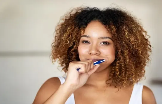 women brushing her teeth to avoid dental caries article banner