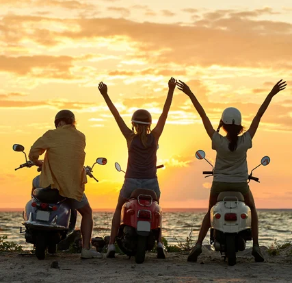3 pessoas com scooter ao pôr do sol