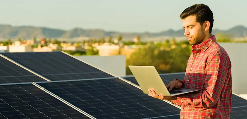 Homem com portátil junto a painéis fotovoltaicos