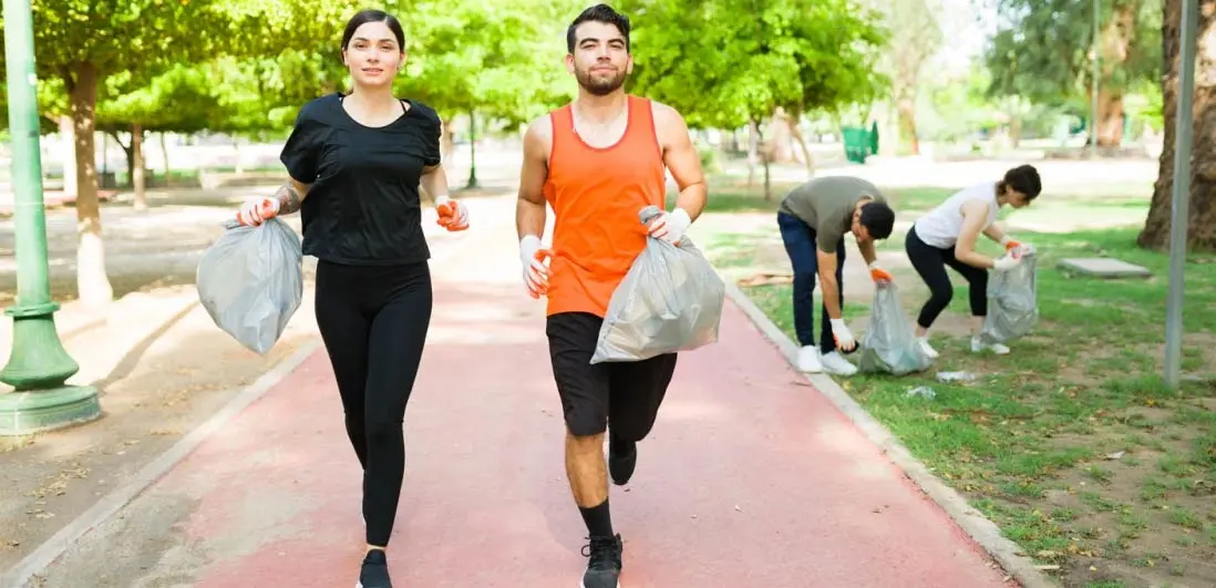 dois jovens a correr com saco de lixo na mão