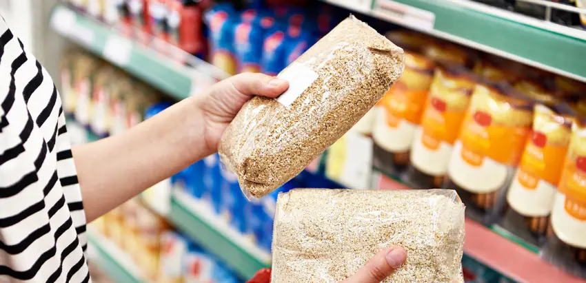 Pessoa segura dois pacotes de cereais. Ao fundo, vê-se a prateleira de um supermercado.