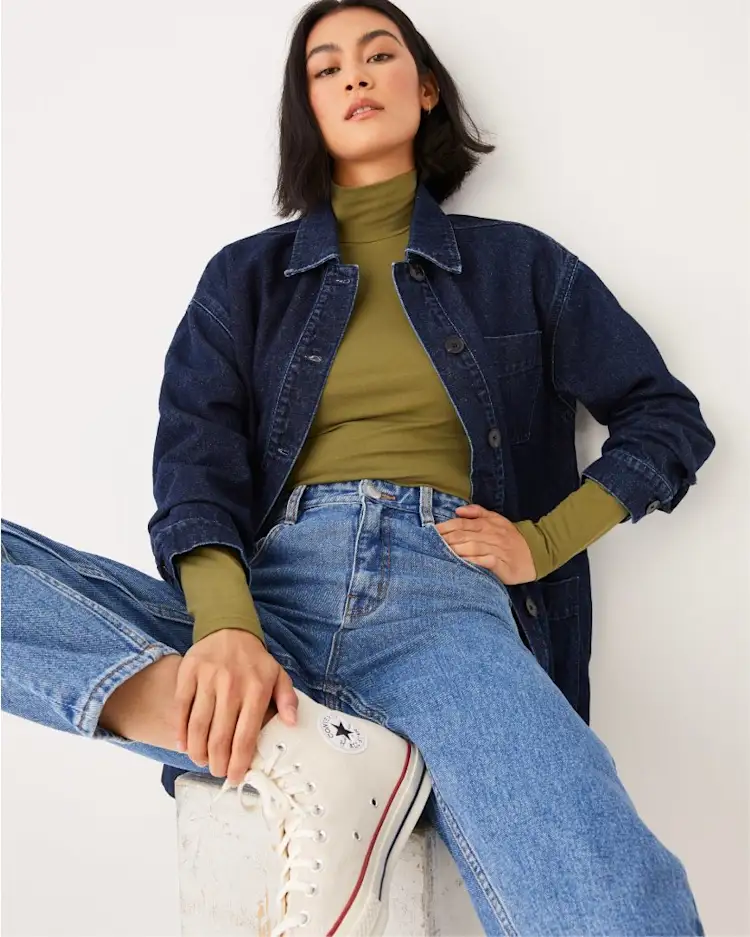 Woman in olive turtleneck sweater with denim jacket
