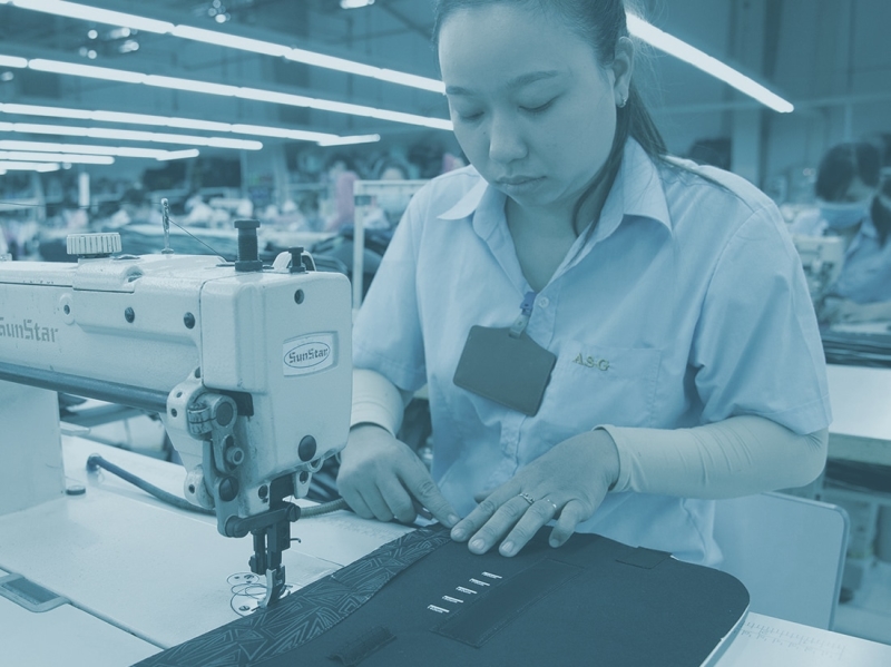 Woman sewing fabrics at production site