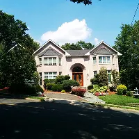 Large suburban home with manicured lawn and driveway on a sunny day.